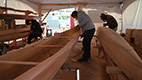 three men working on carving canoes