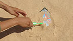 hands using a brush to unearth something in sand